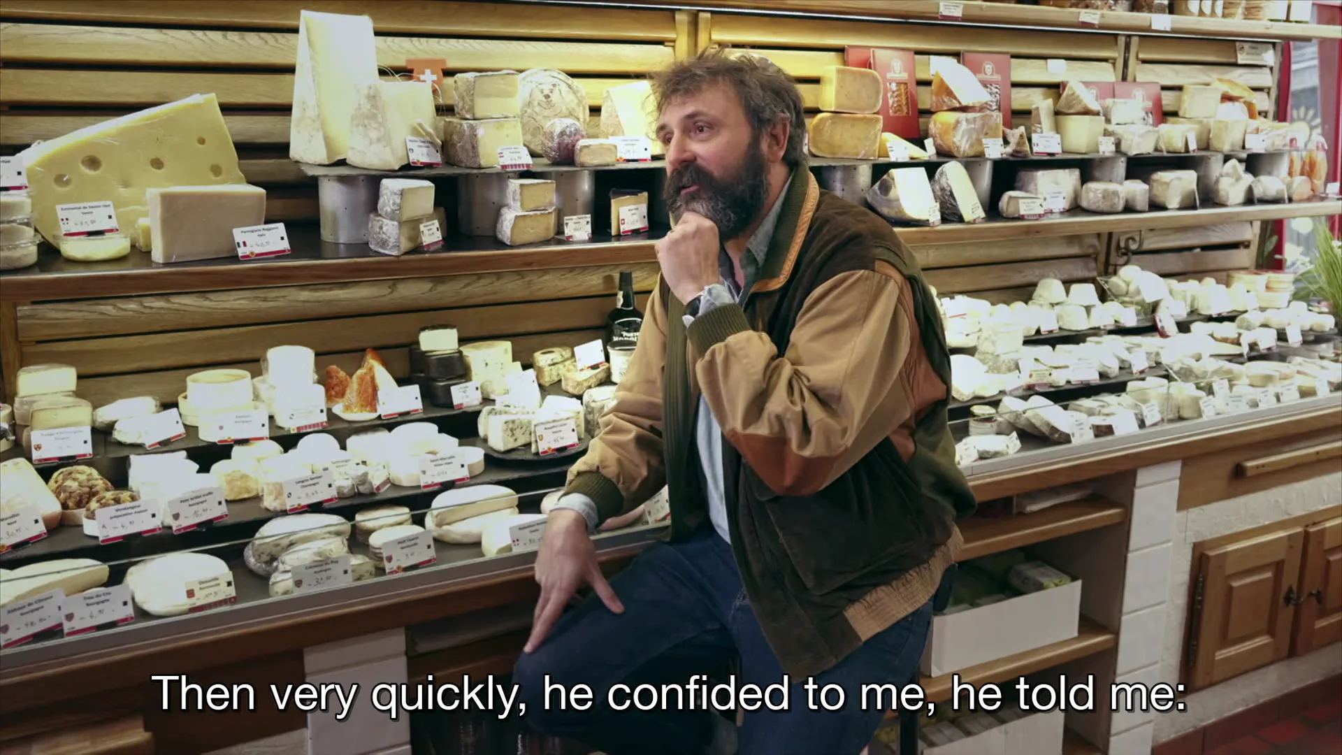 Quentin Dupieux sitting in front of a cheese counter
